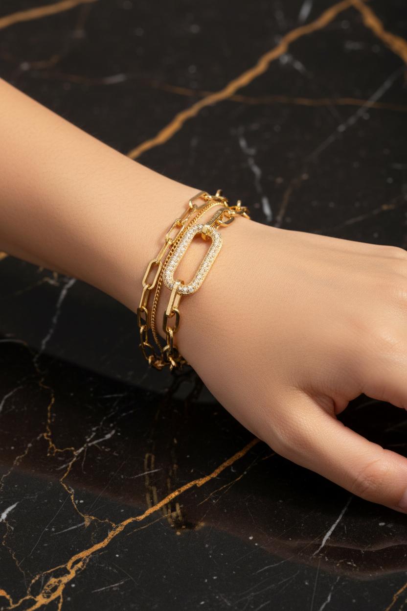 Double-layer gold chain bracelet worn on wrist on black and gold marble