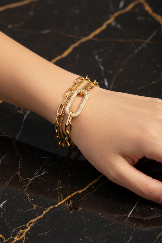 Double-layer gold chain bracelet worn on wrist on black and gold marble